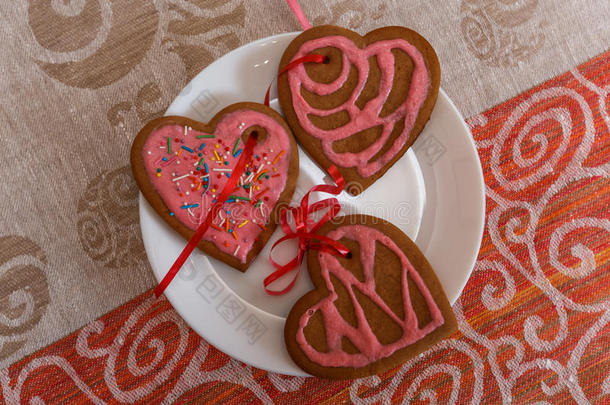 巧克力姜饼饼干心形与红色和粉红色糖衣在白色盘子