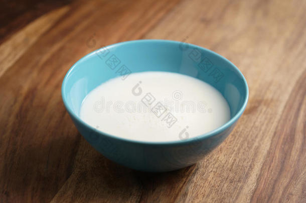 木桌上蓝色碗里的新<strong>鲜牛奶</strong>