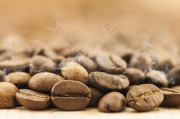 棕色咖啡豆与白色烟雾蒸汽在黄色纹理木板背景关闭。