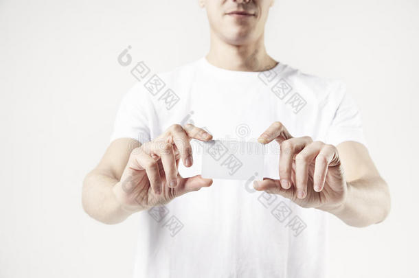 特写男子`手拿名片，穿白色T恤的男子。 工作室的白色背景