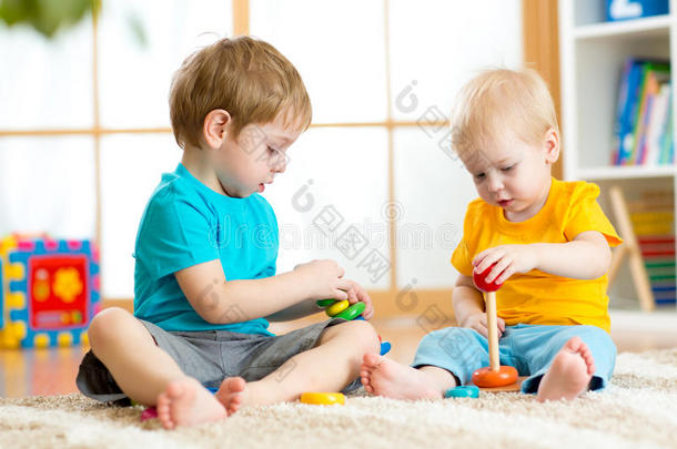 儿童在幼儿园或幼儿园玩教育玩具。 蹒跚学步的孩子和婴儿在家里或家里建造金字塔玩具