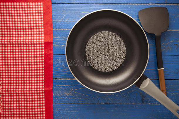 空平底锅，平底锅，平底锅，蓝木背景上有红色桌布。
