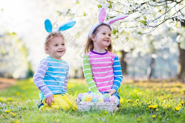 复活节猎蛋。 春天花园里有兔子耳朵的孩子。