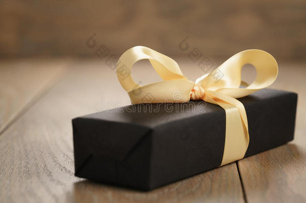 手工礼品黑色纸盒，黄色丝带蝴蝶结在木桌上