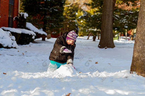有趣的小女孩穿着温暖的<strong>冬季服装</strong>，建造雪人。 孩子在户外玩。