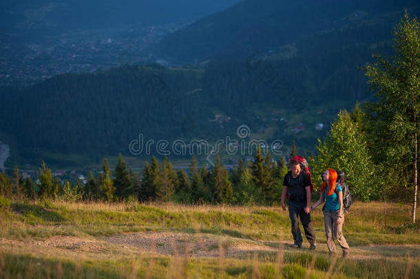 两个背包的徒步旅行者牵着手，在山里散步