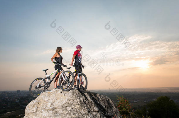 一对夫妇和自行车站在夜空下的岩石上