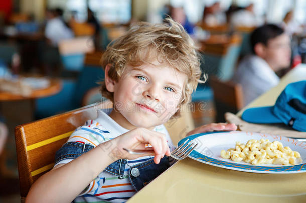 可爱健康的学龄前男孩坐在学校食堂吃意大利面