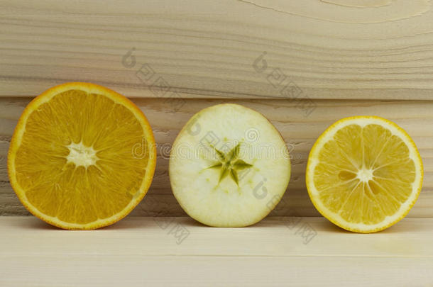 在木制背景上切下新鲜多汁的天然酸苹果、橙色柠檬石灰半