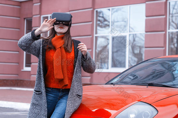 美丽的年轻女孩与虚拟现实VR耳机在红色跑车