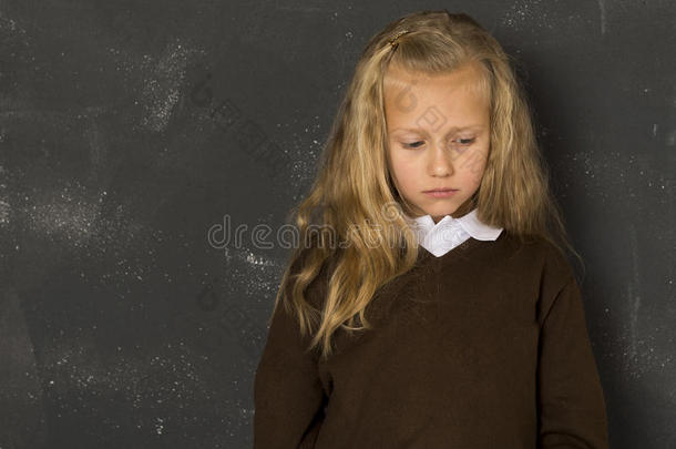 美丽的金发女学生在学校班级黑板前悲伤、喜怒无常和疲倦