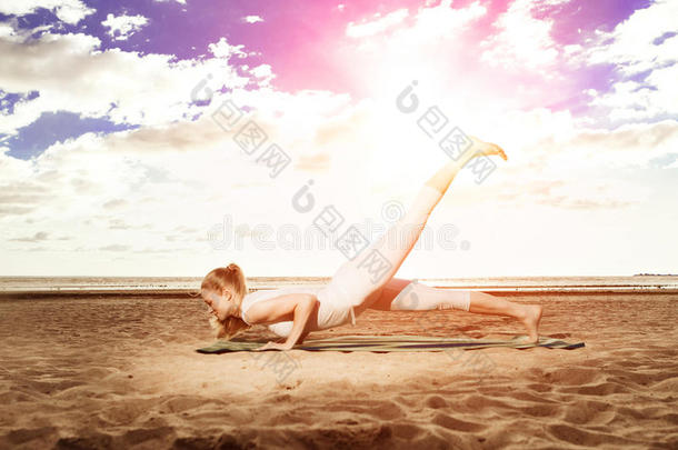 日出时，年轻美丽的苗条女人在海滩上练习瑜伽。日落瑜伽