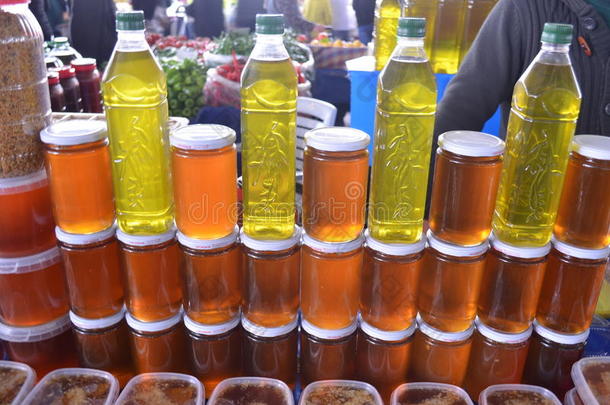 瓶橄榄油和玻璃瓶与蜂蜜在一个摊位和摊位在义卖土耳其安塔利亚