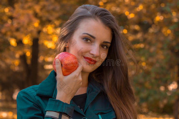 漂亮的女孩把手里的大苹果看起来笔直，微笑着特写