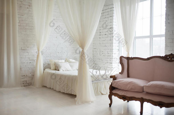卧室采用柔和的浅色。 大舒适优雅的双人床在白色砖阁楼内部与大窗户