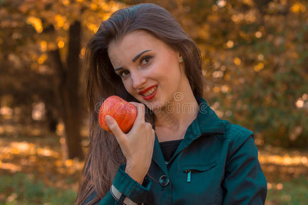 带着红色<strong>口红的</strong>漂亮女孩手里拿着一个苹果，微笑着特写