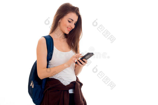开朗聪明的学生女孩穿着棕色运动服，肩上背着背包，看着她的手机和