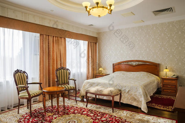 古典卧室有一张大双人床、床头柜、椅子