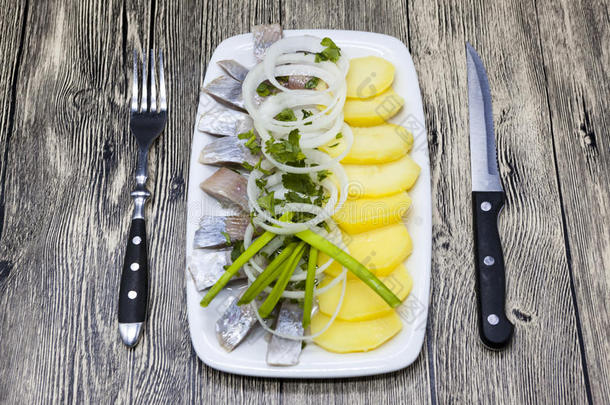 荷兰国家开胃菜，青鱼加洋葱。 美味的冰岛鲱鱼与煮土豆和洋葱在盘子里。
