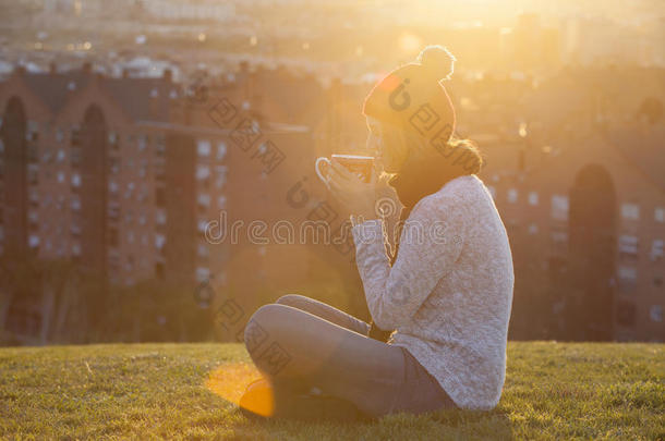 圣诞佳节的女人在公园里日落时喝咖啡