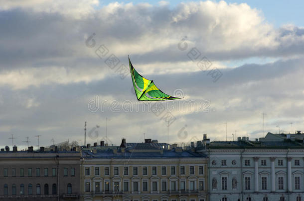 绿色的风筝在天空中飞过城市，建筑物，云彩