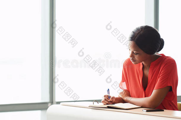非洲女作家坐在窗边忙着工作