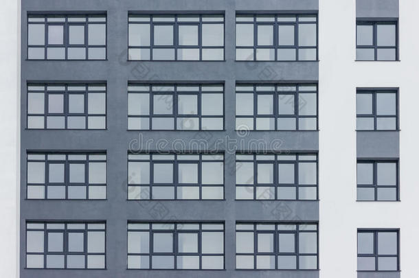 灰色大窗户建筑的深灰色立面。 大的白色条纹。 公寓街区。 家庭。 房地产
