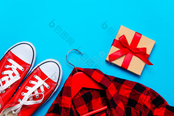<strong>大</strong>红色胶鞋，衣架上的衬衫和美妙的蓝色背景上的美丽礼物