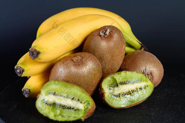 新鲜有机猕猴桃、草莓、香蕉和半石榴石在黑色圆形、新鲜水果、早上好食物上的位置。