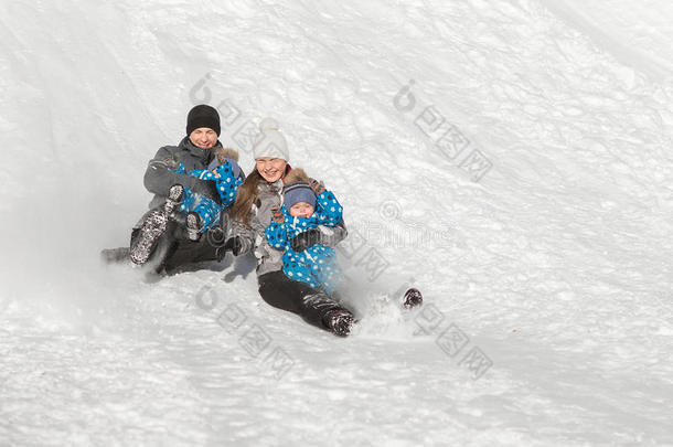 一个四口之家带着双胞胎在公园的冬天滑下了雪山