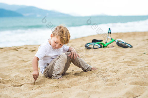 活跃的金发男孩和自行车在海边。 蹒跚学步的孩子在温暖的夏天做梦和玩得开心。 户外游戏给孩子