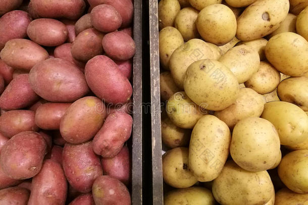 新鲜的有机土豆和红薯在超市篮子里的许多土豆背景中脱颖而出。 一堆土豆根。 CL