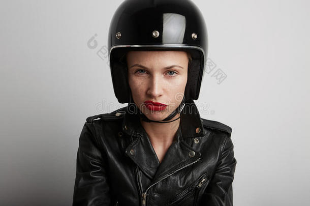 在白色背景下，穿着时尚的黑色运动头盔和皮夹克的自行车女子的特写肖像。