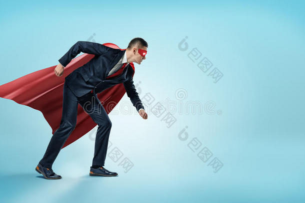 一个穿着超级英雄红色斗篷和面具的商人站在蓝色背景的<strong>起跑</strong>线位置。