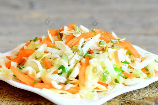 简单的自制凉拌沙拉。 美味的卷心菜沙拉，胡萝卜，洋葱和南瓜子在盘子和木桌上