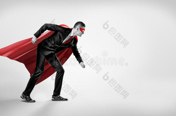 一个穿着超级英雄红色斗篷和面具的商人站在灰色背景上的<strong>起跑</strong>线位置。