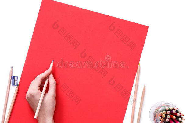 女手准备用蓝色铅笔在红纸上画画。 在白色上隔离。