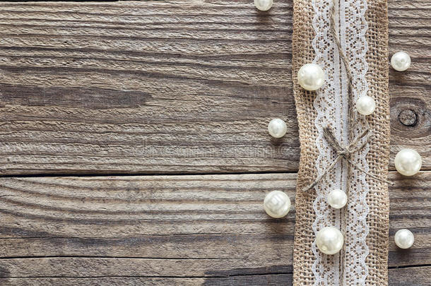 旧木桌上有白色花边和珠子的麻布边框。