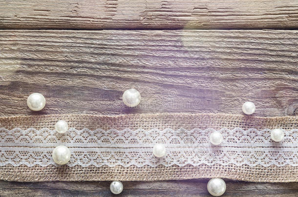 旧木桌上有白色花边和珠子的麻布边框。