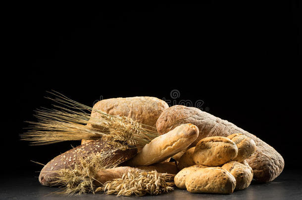 黑木桌子上的<strong>面包</strong>、<strong>面包</strong>、<strong>面包</strong>和<strong>面包</strong>。 黑巴上的黑麦、大麦、小麦、燕麦和许多新鲜混合<strong>面包</strong>
