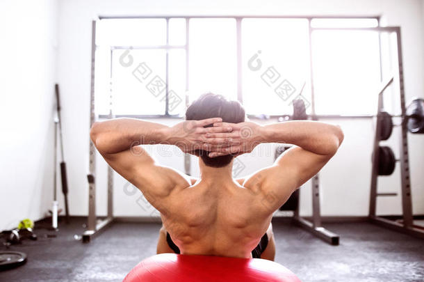 适合西班牙裔男子在健身房训练，工作<strong>腹肌</strong>，做仰卧起坐