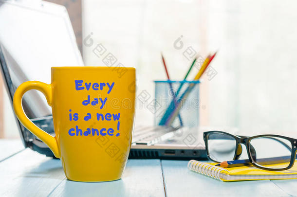 每一天都是一个新的机会。 在商务办公室背景下激励早上咖啡杯上的文字