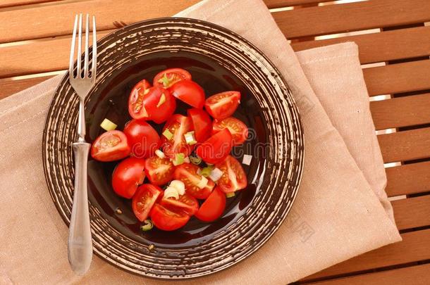 新鲜健康的纯素沙拉，<strong>红色</strong>西红柿和洋葱在深色盘子上，叉子在棕色<strong>布</strong>上，木底