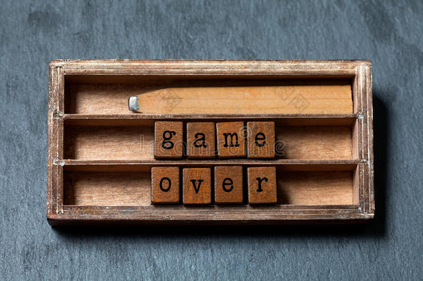 游戏超过报价和失败的概念。 老式盒子，木制立方体与旧风格的字母，复古风格的铅笔。 灰色的石头