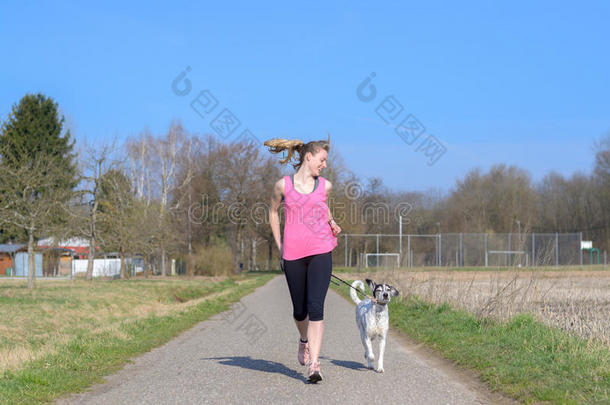 适合运动的年轻女人和她的狗<strong>一起跑</strong>步