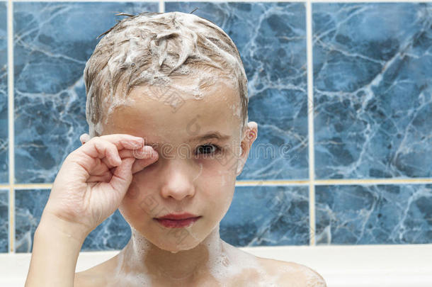 可爱的小男孩用洗发水肥皂在洗头发上洗澡。 CL