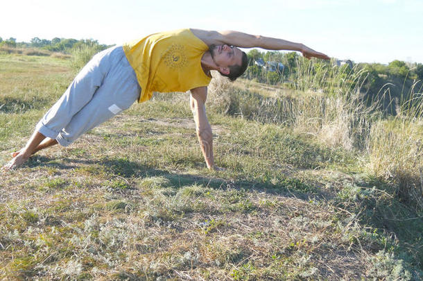练习<strong>瑜伽动作</strong>和户外姿势的人。 站在瑜伽姿势上的年轻人在大自然中。 运动员在做力量