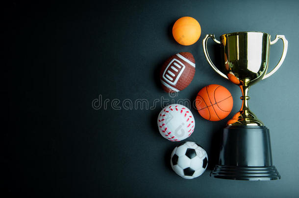 金色奖杯，足球玩具，棒球玩具，乒乓球，篮球玩具和橄榄球玩具隔离在黑色背景与复制sp
