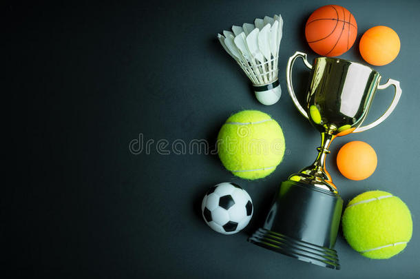 金色奖杯，足球玩具，棒球玩具，乒乓球，羽毛球和网球隔离在黑色背景与副本
