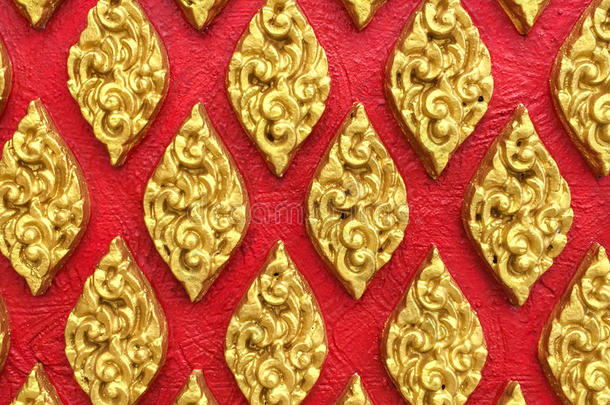 经典石刻泰国复古风格艺术的金色花无缝图案在红色混凝土背景纹理上用作美化